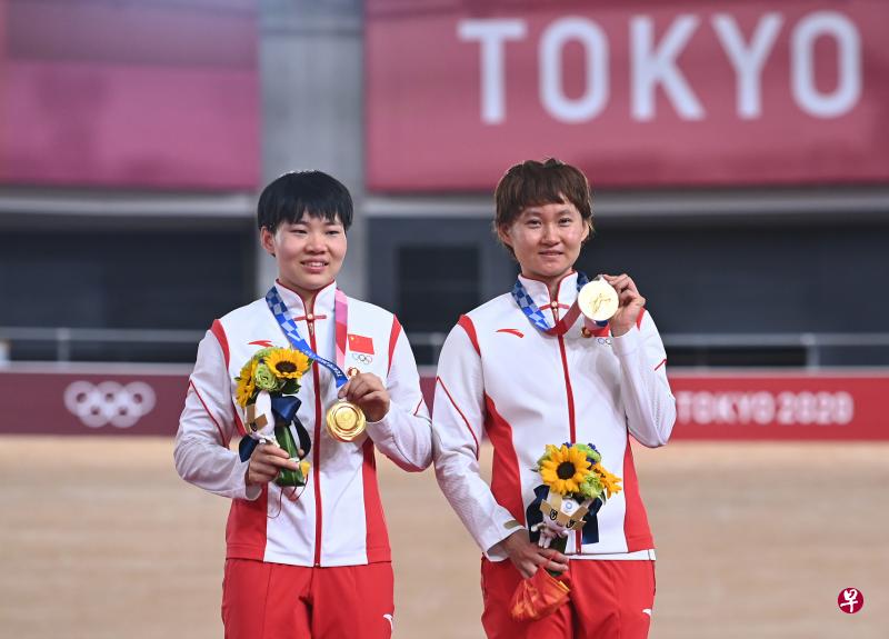 中国场地自行车老将钟天使(右)和搭档鲍珊菊(左)本月2日在东京奥运女子团体竞速赛夺金后,配戴毛泽东像章上台领奖。(新华社)